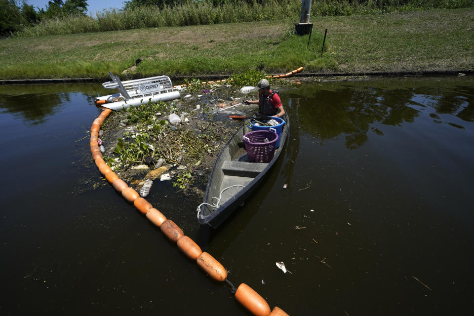 Jack Bates, of Osprey Initiative, collects trash that was captured by the company’s Litter Gitter, which catches trash in waterways in nine states before it can travel into larger bodies of water, in New Orleans, Friday, May 27, 2022. Many novel devices are being used or tested worldwide to trap plastic trash in rivers and smaller streams before it can get into the ocean. (AP Photo/Gerald Herbert)