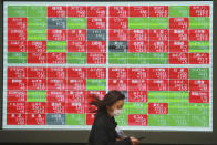 A woman walks by an electronic stock board of a securities firm in Tokyo, Wednesday, Dec. 2, 2020. Asian markets are mixed after the U.S. benchmark S&P 500 set another record. (AP Photo/Koji Sasahara)