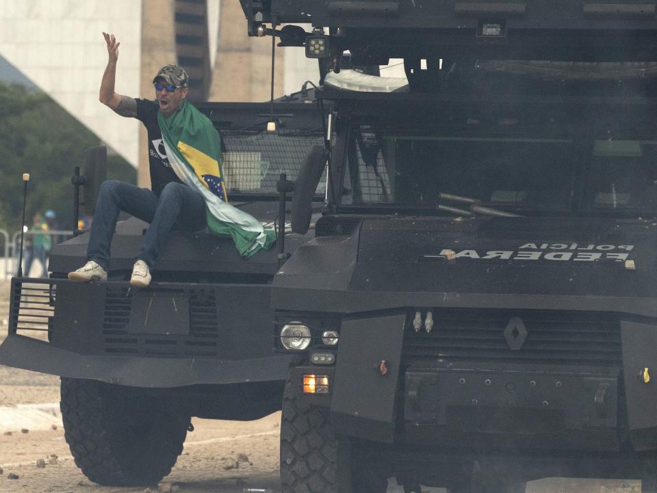 A supporter of former President Jair Bolsonaro sits on top of a security vehicle