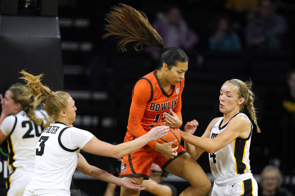 Bowling Green guard Keiryn McGuff, center, fights for a rebound with Iowa guard Sydney Affolter (3) and guard Kylie Feuerbach (4) during the first half of an NCAA college basketball game, Saturday, Dec. 2, 2023, in Iowa City, Iowa. (AP Photo/Charlie Neibergall)