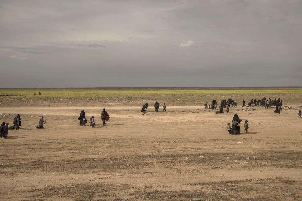 In this Wednesday, March 6, 2019, photo, women and children walk to a reception area for people evacuated from the last shred of territory held by Islamic State militants, outside Baghouz, Syria. (AP Photo/Gabriel Chaim)