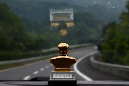 A bust of former Chinese leader Mao Zedong sits on the dashboard of a taxi as it drives through the mountains near Jinggangshan, Jiangxi province, China, September 14, 2017. REUTERS/Thomas Peter