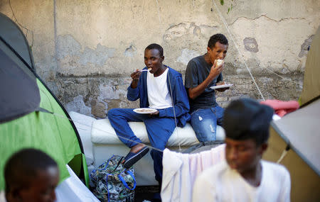 Migrants eat after getting food from volunteers at a makeshift camp in Via Cupa (Gloomy Street) in downtown Rome, Italy, August 1, 2016. REUTERS/Max Rossi