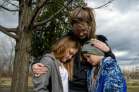 Vanessa LaBrie holds onto her two children, Kiersteyn Fields, 10, and her brother Landon Baker, 8 , as they stand in their yard up the road from Oxford High School on Thursday, Dec. 2, 2021 in Oxford, Mich. A 15-year-old sophomore opened fire at his Michigan high school on Tuesday, killing four students, including a 16-year-old boy who died in a deputy’s patrol car on the way to a hospital, authorities said. (Jake May/The Flint Journal via AP)