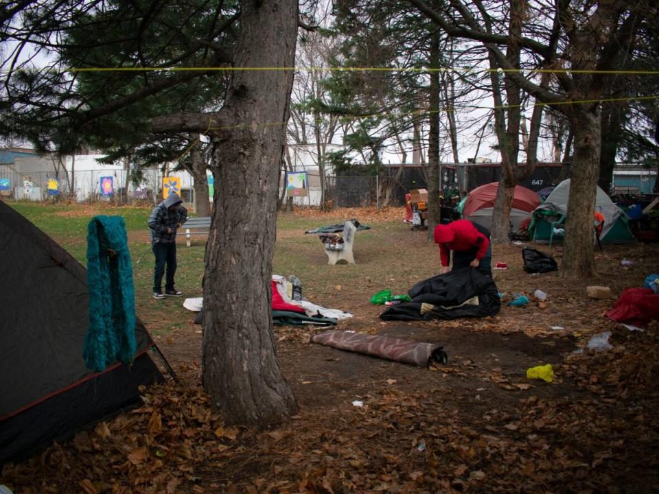 Two volunteers help move a tent in an encampment in Hamilton's east end last December. (Bobby Hristova/CBC - image credit)