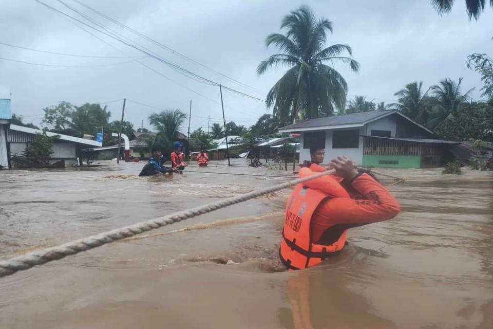 In this photo provided by the Philippine Coast Guard, rescuers use ropes as they evacuate residents from flooded areas due to Tropical Storm Nalgae at Parang, Maguindanao province, southern Philippines on Friday Oct. 28, 2022. Floodwaters rapidly rose in many low-lying villages, forcing some villagers to climb to their roofs, where they were rescued by army troops, police and volunteers, officials said. (Philippine Coast Guard via AP)