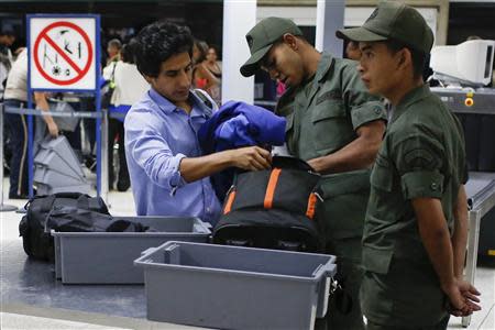 Soldiers checks the luggage of a passenger in a security checkpoint at the Simon Bolivar airport in La Guaira outside Caracas October 15, 2013. REUTERS/Carlos Garcia Rawlins