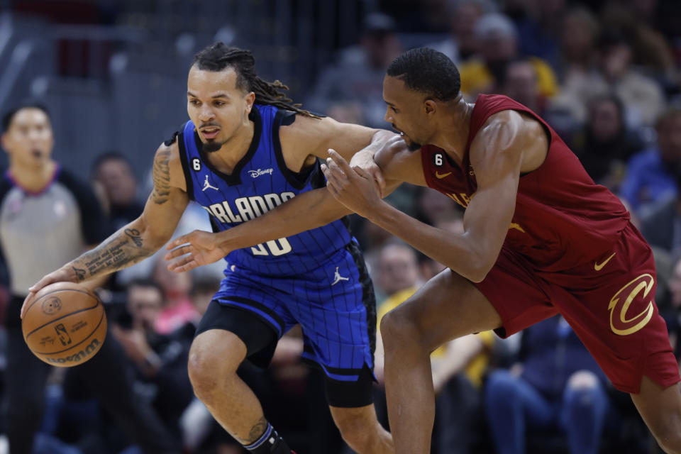 Orlando Magic guard Cole Anthony, left, controls the ball against Cleveland Cavaliers forward Evan Mobley, right, during the second half of an NBA basketball game, Friday, Dec. 2, 2022, in Cleveland. (AP Photo/Ron Schwane)