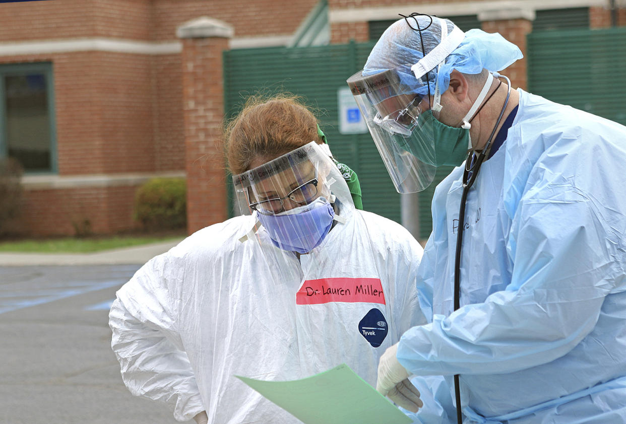 Dr. Lauren Miller, left, and Dr. Micah Moore look over notes at a Mobile Health Unit for drive-thru coronavirus testing at Robert C. Byrd Clinic on the campus of the West Virginia School of Osteopathic Medicine in Lewisburg, W.Va., Tuesday, March 24, 2020. The nurses and doctors can test for COVID-19, but also treat flu and allergy symptoms.  "It's a full medical appointment from the comfort of your own car," Miller said. (Jenny Harnish/The Register-Herald via AP)