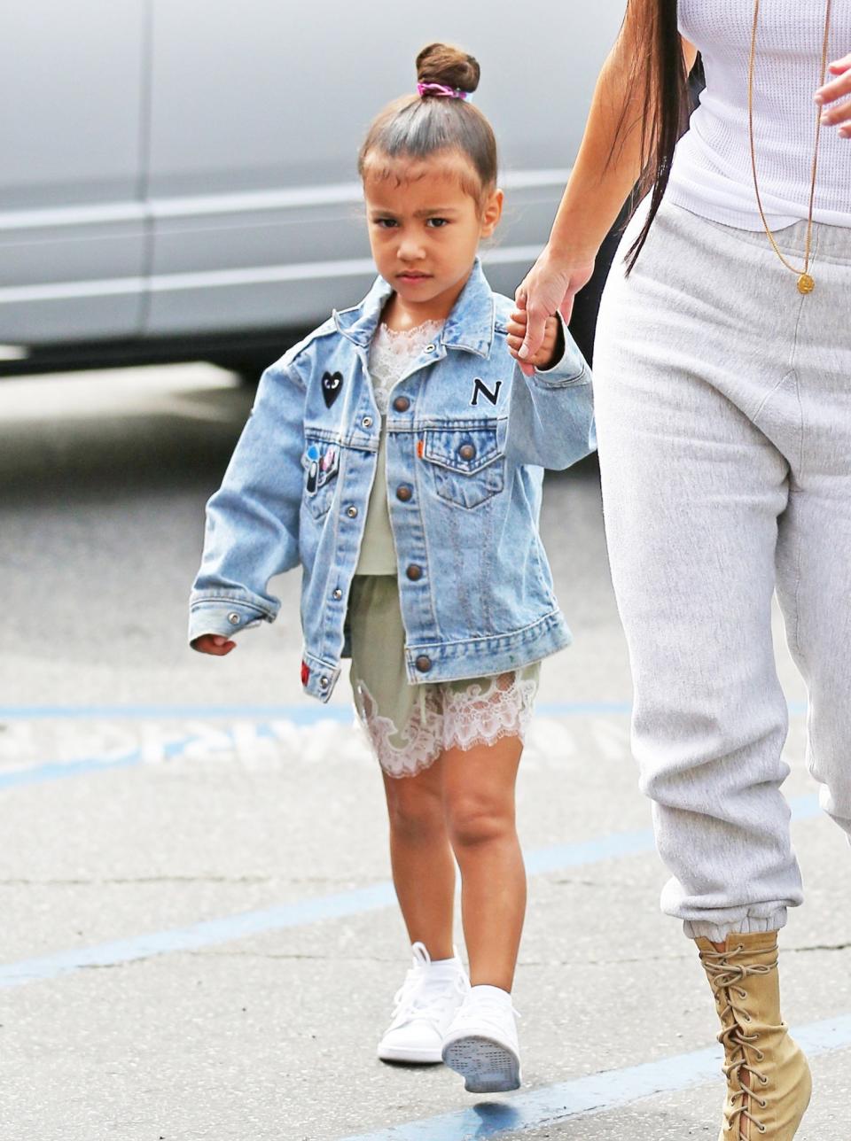 <p>Here with her personalized over-sized denim jacket, over a mint green lace slip dress. North West knows what’s what. (Photo: Backgrid) </p>