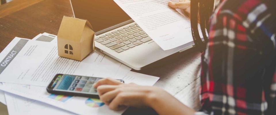 Woman looking at health insurance documents, adding things up with a calculator