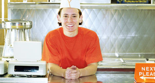 Teenage boy (17-19) working behind counter of fast-food restaurant