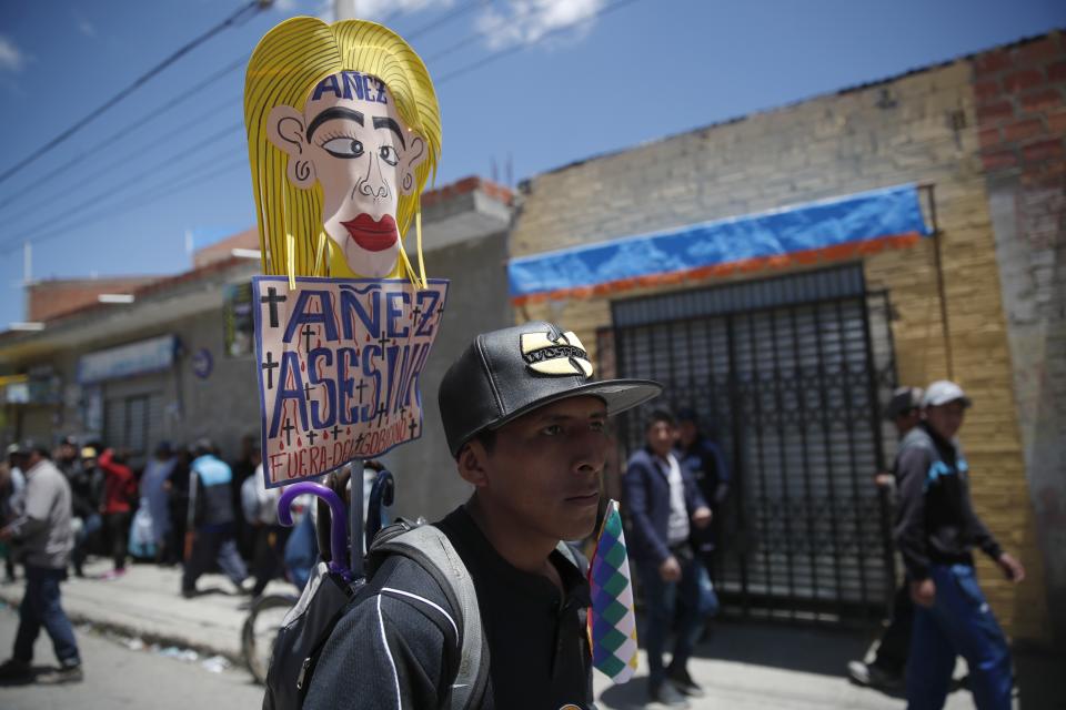 A supporter of former President Evo Morales holds a sign with a handwritten message that reads in Spanish: "Jeanine Añez assassin, Get out" in reference to Bolivia's interim president, during a protest in El Alto, on the outskirts of La Paz, Bolivia, Wednesday, Nov. 20, 2019. Bolivia has been in a state of turbulence since a disputed Oct. 20 vote. Morales resigned Nov. 10, but his supporters oppose the interim government that took his place. (AP Photo/Natacha Pisarenko)