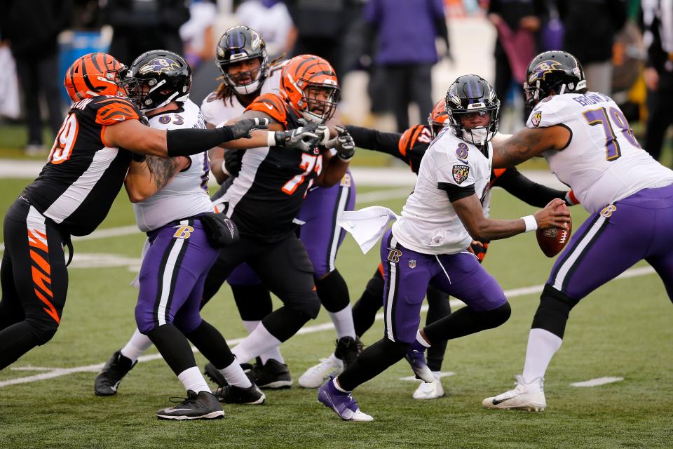 Baltimore Ravens quarterback Lamar Jackson (8) evades tackles as he scrambles in the first quarter of the NFL Week 17 game between the Cincinnati Bengals and the Baltimore Ravens at Paul Brown Stadium in downtown Cincinnati on Sunday, Jan. 3, 2021. The Ravens led 17-3 at half time. 