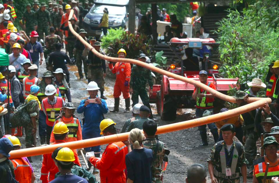 <em>Rescuers carry water pipe as they make their way up at the entrance to the cave complex (AP)</em>