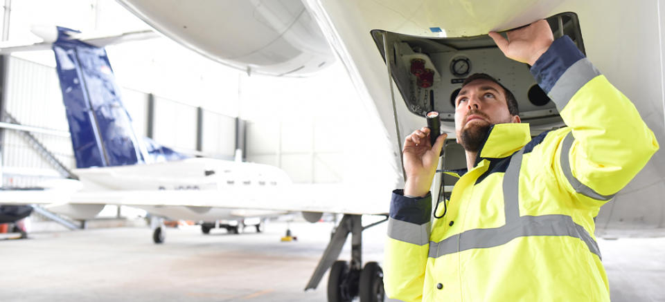 Airport worker completes an aircraft safety check in hangar