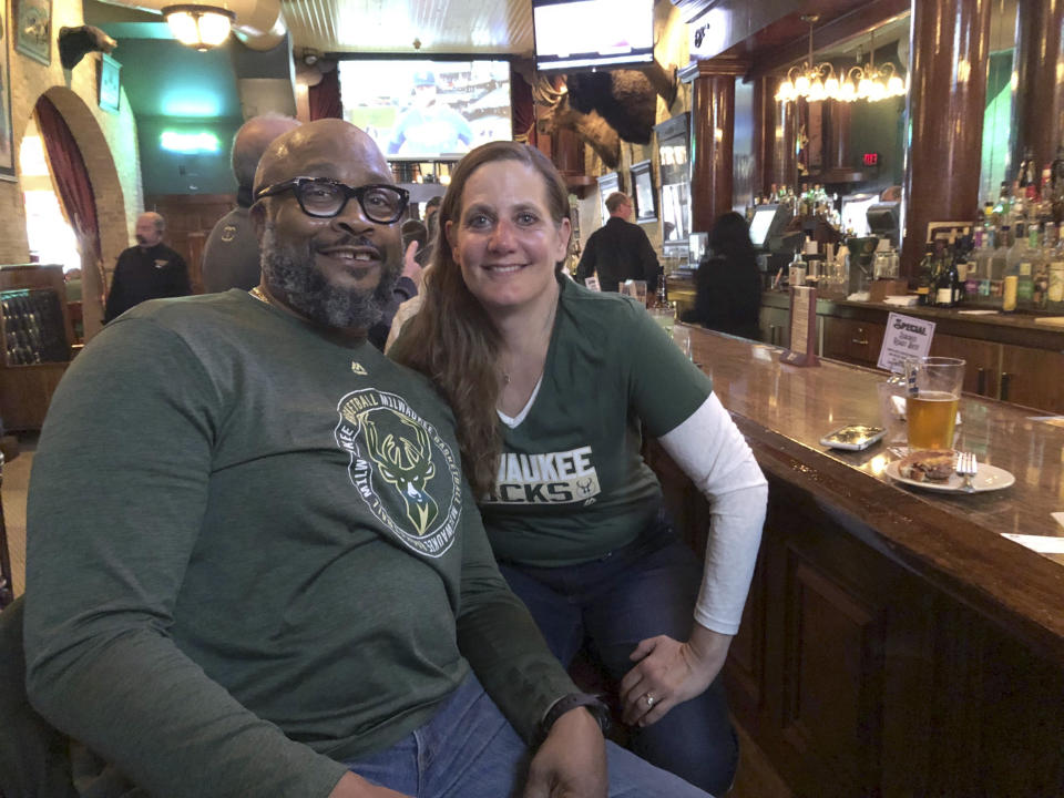 In this May 8, 2019 photo, longtime Bucks fans and season-ticket holders, Rod Johnson and his wife, Therese, both from Milwaukee, pose for a photo at a bar near the stadium before last Wednesday's game. (AP Photo/Ivan Moreno)