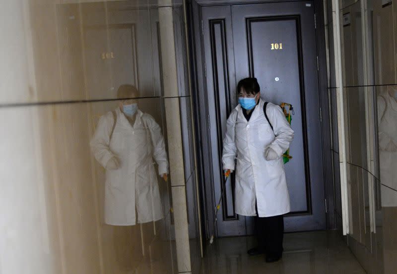 Worker Gong Lixia wearing a face mask sprays disinfectant to sanitize an apartment building at a residential compound, as the country is hit by an outbreak of the novel coronavirus, in Beijing