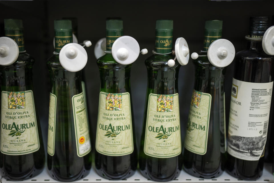 Bottles of virgin olive oil, sealed with an anti-theft system, are photographed on a shelf in a shop in Barcelona, Spain, Tuesday, June 25, 2024. Spain will temporarily eliminate sales tax on olive oil to help consumers cope with skyrocketing prices, the government said Tuesday. (AP Photo/Emilio Morenatti)