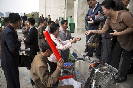 FILE PHOTO: People use North Korean won and U.S. dollars to buy inflatable clappers at a black market exchange rate before a football match at the Kim Il Sung Stadium in Pyongyang October 8, 2015. REUTERS/Damir Sagolj/File Photo
