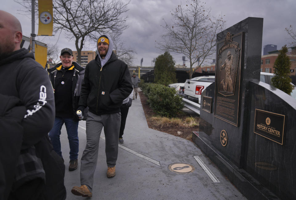 Pittsburgh Steelers fans walk past a marker commemorating the exact spot where the 1972 "Immaculate Reception," was made by Franco Harris at Three Rivers Stadium, which once stood on the North Side of Pittsburgh, on Sunday, Dec. 11, 2022, in Pittsburgh, Pa. Harris' scoop of a deflected pass and subsequent run for the winning touchdown in a 1972 playoff victory against Oakland has been voted the greatest play in NFL history and celebrates its 50th anniversary this year. (AP Photo/Jessie Wardarski)