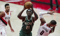 Milwaukee Bucks guard Jrue Holiday, center, drives to the basket past Portland Trail Blazers guard Damian Lillard, right, during the second half of an NBA basketball game in Portland, Ore., Friday, April 2, 2021. (AP Photo/Craig Mitchelldyer)