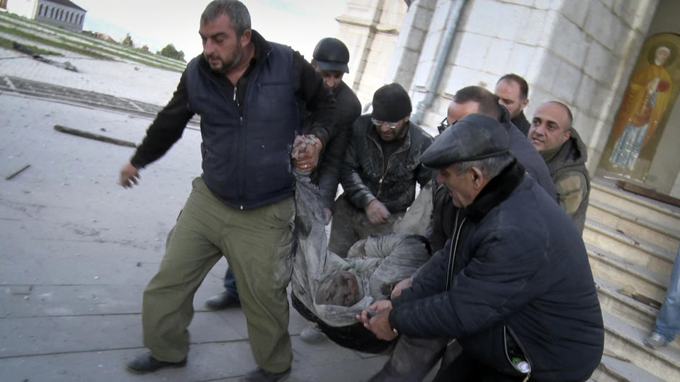 In this image taken from a video provided by ArmNews TV, people carry out an injured man from the Holy Savior Cathedral after shelling the Cathedral by Azerbaijan's artillery during a military conflict, in Shushi, outside Stepanakert, self-proclaimed Republic of Nagorno-Karabakh, Thursday, Oct. 8, 2020. (ArmNews TV via AP)