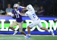 Washington wide receiver Jalen McMillan, left, fends off a tackle by Tulsa linebacker Zach Neilsen during the second half of an NCAA college football game Saturday, Sept. 9, 2023, in Seattle. (AP Photo/Lindsey Wasson)