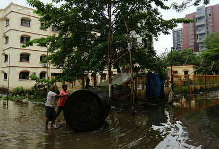 Men push a water tank through a partially flooded street at a residential area in Mumbai, India, August 30, 2017. REUTERS/Danish Siddiqui