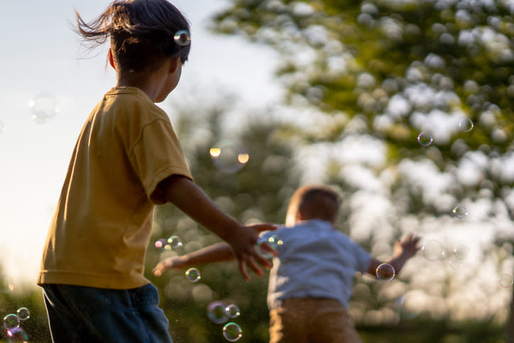 Two children play with bubbles outdoors
