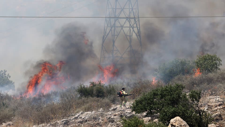 An Israeli firefighter walks near the flames in a field after rockets launched from southern Lebanon landed on the outskirts of Alma in the Israel-annexed Golan Heights in Syria on Tuesday. - Jack Guez/AFP/Getty Images