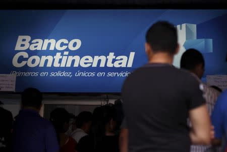 People stand outside a branch of Banco Continental, hours after the Honduran government ordered its liquidation, in Tegucigalpa, Honduras, October 12, 2015. REUTERS/Jorge Cabrera