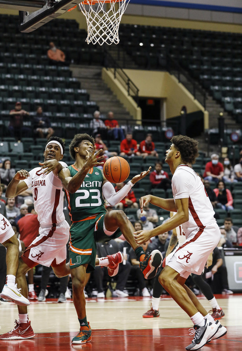 Miami guard Kameron McGusty, center, tries to grab a rebound in between Alabama forward Noah Gurley, left, and Alabama forward Darius Miles, right, during the first half of an NCAA college basketball game Sunday, Nov. 28, 2021, in Lake Buena Vista, Fla. (AP Photo/Jacob M. Langston)