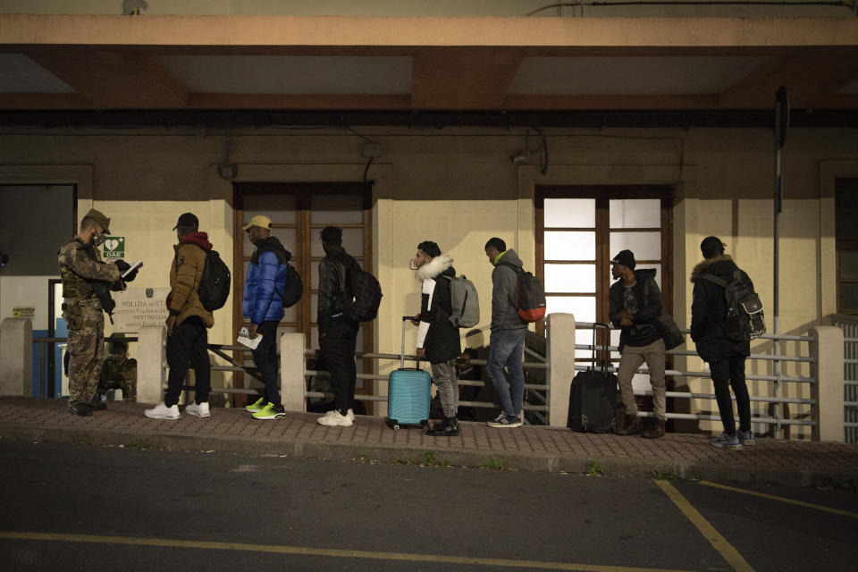 Migrants line up to be checked by Italian authorities at the Italian French border of Ventimiglia, Italy, Saturday, Nov. 12, 2022. (Marco Alpozzi/LaPresse via AP)