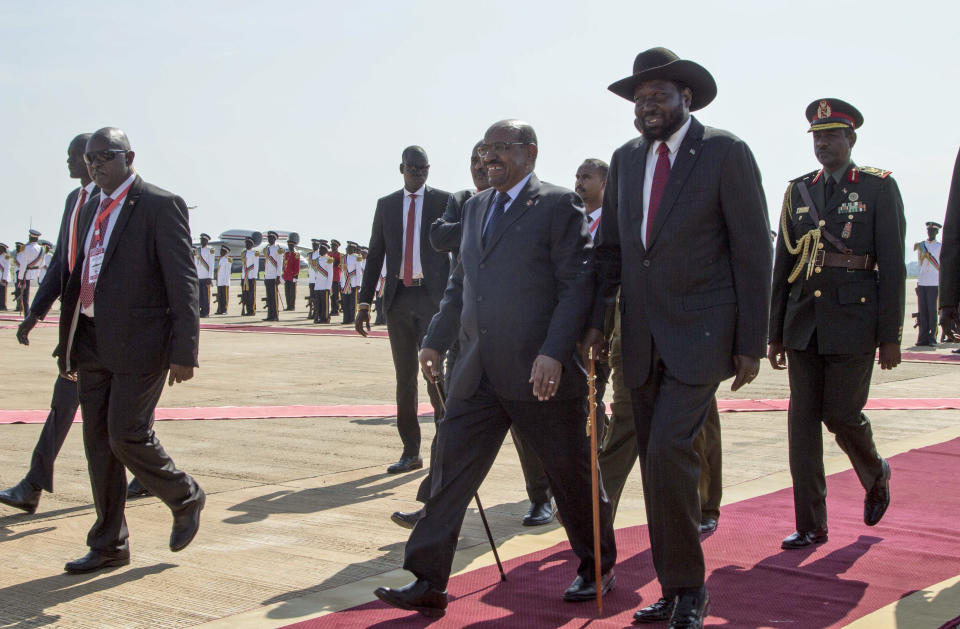 Sudan's President Omar al-Bashir, center, walks with South Sudan's President Salva Kiir, center right, as he arrives at the airport in Juba, South Sudan Wednesday, Oct. 31, 2018. For the first time since fleeing the war-torn country more than two years ago, South Sudan's opposition leader Riek Machar returned on Wednesday to take part in a nationwide peace celebration. (AP Photo/Bullen Chol)