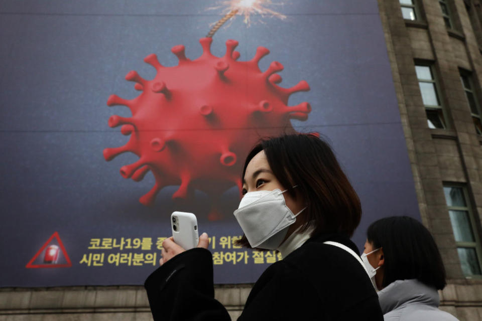 People wearing masks to prevent the spread of COVID-19 walk in front of a banner emphasizing an enhanced social distancing campaign displayed on the wall of Seoul City Hall on November 25, 2020 in Seoul, South Korea. Authorities announced the tightening of social distancing regulations and the closure of some kinds of businesses, including nightclubs, to combat a quickly increase wave of Covid-19 infections this week. <span class="copyright">Chung Sung-Junâ€“Getty Images</span>