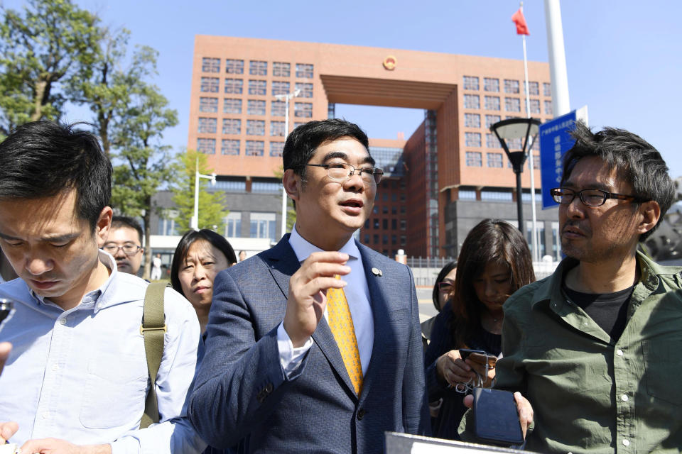 Chen Weixiong, center, lawyer of former Japanese politician Takuma Sakuragi, leaves the Guangzhou City First Intermediate Court, seen in the background, after a sentencing in Guangzhou, southern China Friday, Nov. 8, 2019. The court on Friday sentenced Sakuragi to life in prison in a 5-year-old drug trafficking case. (Naohiko Hatta/Kyodo News via AP)