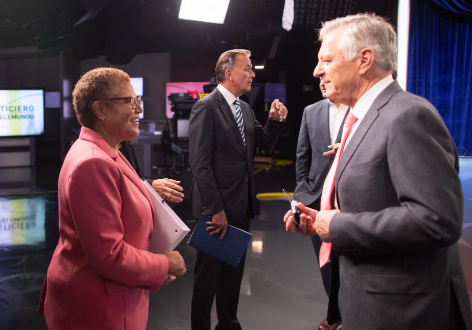 Rep. Karen Bass, in salmon-colored suit, in conversation with Conan Nolan as other people stand by after the debate.