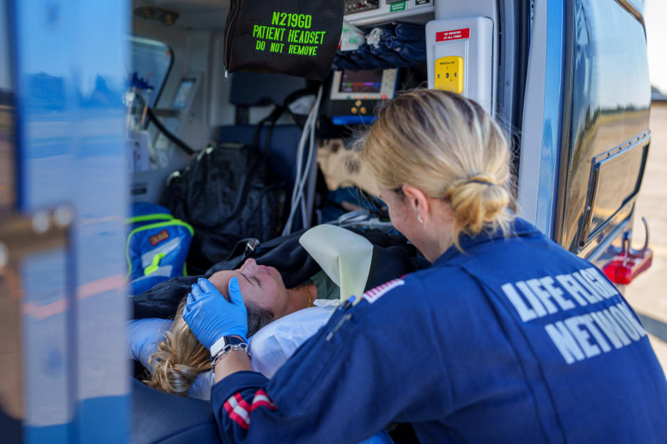A paramedic tends to a woman inside a helicopter.