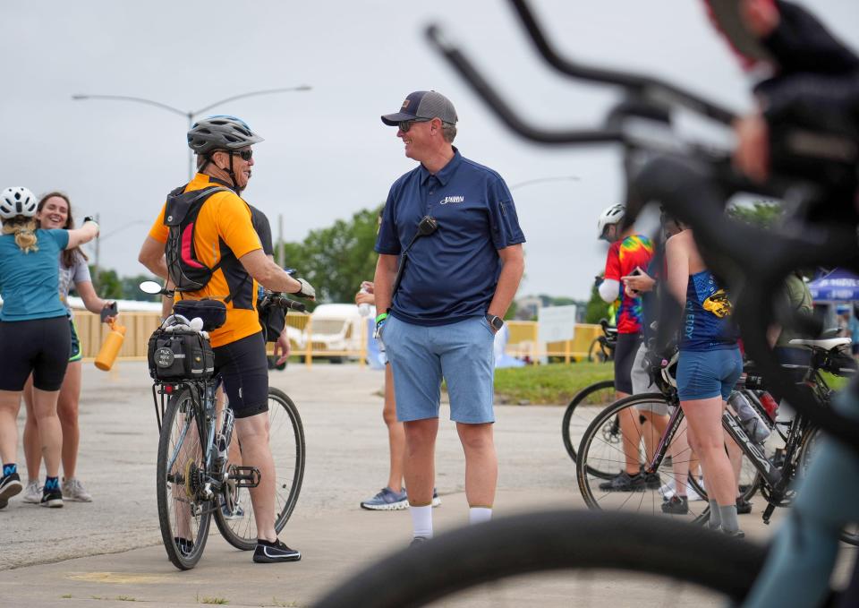 RAGBRAI director Matt Phippen visits with cyclists at the Mississippi River tire dip site Saturday as RAGBRAI's 50th anniversary ride reaches its destination, Davenport.