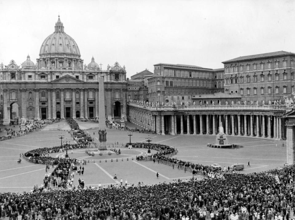 FILE - This June 5, 1963 file photo shows a general overhead view of St. Peter's Square as a huge crowd moves on continuously into St. Peter's (background) where Pope John XXIII, who died June 3, lies in state. In order to avoid crush and confusion next to the Basilica the crowd is kept on the outskirts of the Square and then let through police cordons and wooden fences across the Square up to the Basilica. Upper right is the Apostolic Palace where the Pontiff died in his apartment on top floor. While much of the focus of Sunday's dual canonization will be on Pope John Paul II's globe-trotting, 26-year papacy and his near-record sprint to sainthood, many older Catholics will be celebrating the short but historic pontificate of the "Good Pope," John XXIII. (AP Photo/File)