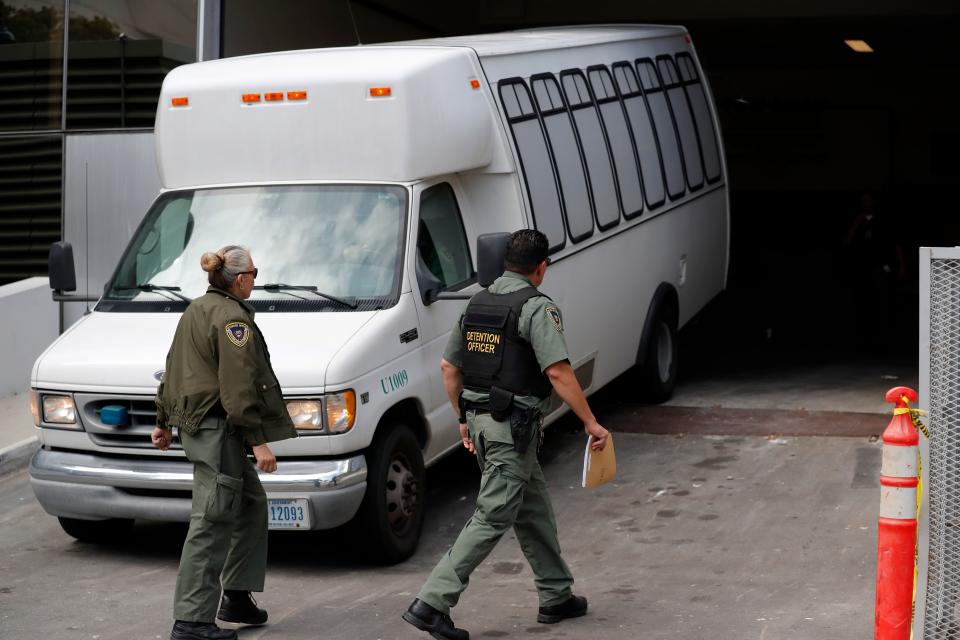 In this Tuesday, March 19, 2019 file photo, a van carrying asylum seekers from the border is escorted by security personnel as it arrives at immigration court, in San Diego. A federal appeals court ruled Tuesday, May 7, 2019, that the Trump administration can force asylum seekers to wait in Mexico for immigration court hearings while the policy is challenged in court, handing the president a major victory, even if it proves temporary.
