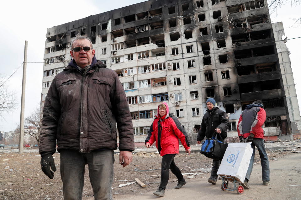 People walk near a block of flats, which was destroyed during Ukraine-Russia conflict in the besieged southern port city of Mariupol, Ukraine March 17, 2022. REUTERS/Alexander Ermochenko