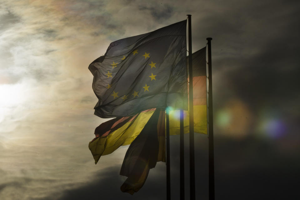 FILE - A European, left, and two German flags fly under a cloudy sky at the Place of the Republic in Berlin, Thursday, Dec. 8, 2011. German politics are in a disgruntled, volatile state as the country's voters prepare to fill 96 of the 720 seats at the European Parliament on June 9, the biggest single national contingent in the 27-nation European Union. It's the first nationwide vote since center-left Chancellor Olaf Scholz took power in late 2021. (AP Photo/Markus Schreiber, File)