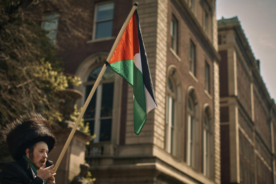 An Ultra-Orthodox Jewish man holds a Palestinian flag in support of the pro-Palestinian encampment, advocating for financial disclosure and divestment from all companies tied to Israel and calling for a permanent cease-fire in Gaza, outside Columbia University campus on Sunday, April 28, 2024, in New York. (AP Photo/Andres Kudacki)