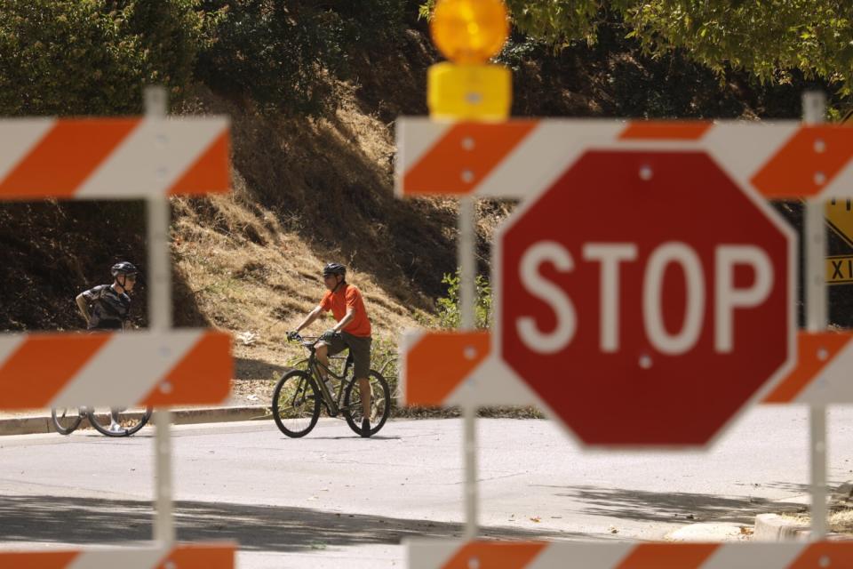 Cyclists talk behind a sign blocking out cars