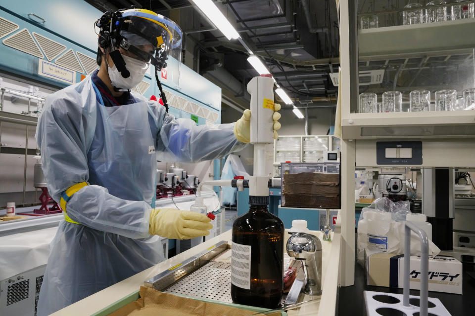A lab technician wearing a pair of smart glasses demonstrates a part of a process to measure levels of tritium in water samples at one of the two laboratories at the Fukushima Daiichi nuclear power plant, run by Tokyo Electric Power Company Holdings, in Okuma town, northeastern Japan, Thursday, March 3, 2022. TEPCO and government officials say tritium, which is not harmful in small amounts, is inseparable from the water, but all other 63 radioactive isotopes selected for treatment can be reduced to safe levels, tested and further diluted by seawater before release. (AP Photo/Hiro Komae)