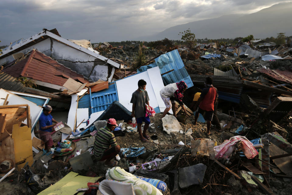 In this Friday, Oct. 5, 2018, file photo, a family scavenges for salvageable items from the ruins of their house at Petobo neighborhood which was wiped out by liquefaction caused by a massive earthquake in Palu, Central Sulawesi, Indonesia. (AP Photo/Dita Alangkara, File)