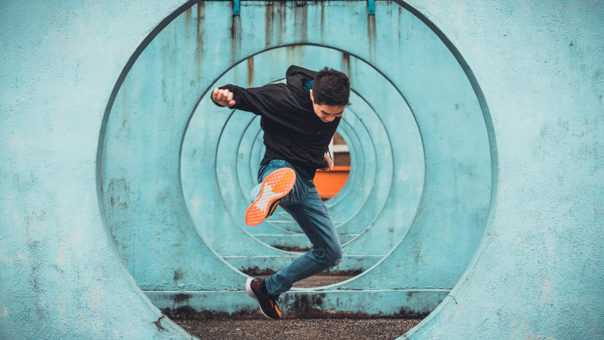 Young Asian active man in action of jumping and kicking, circle looping wall background.