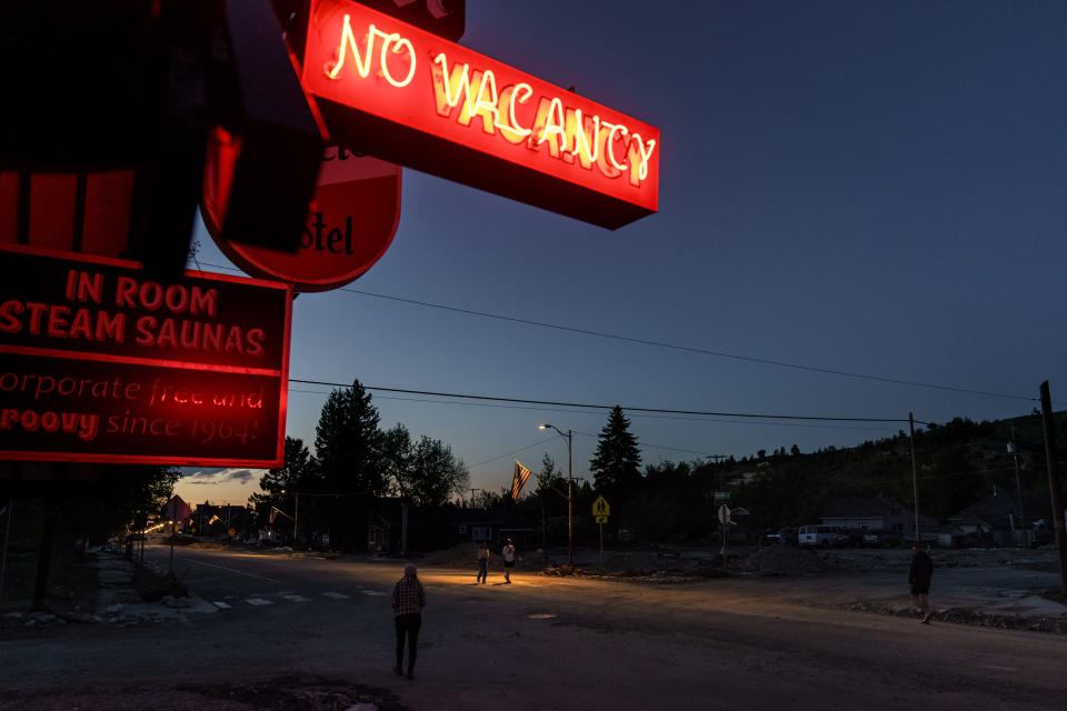 Pedestrians pass a motel in Red Lodge, Mont., while surveying the damage after floodwaters receded, Wednesday, June 15, 2022. (AP Photo/David Goldman)